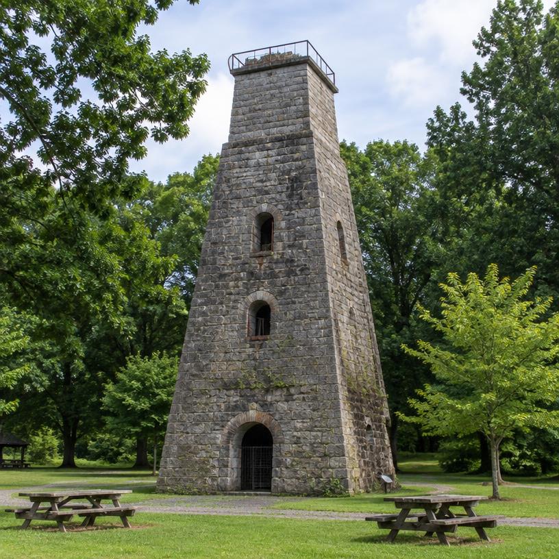 Historic stone iron furnace tower in a green park